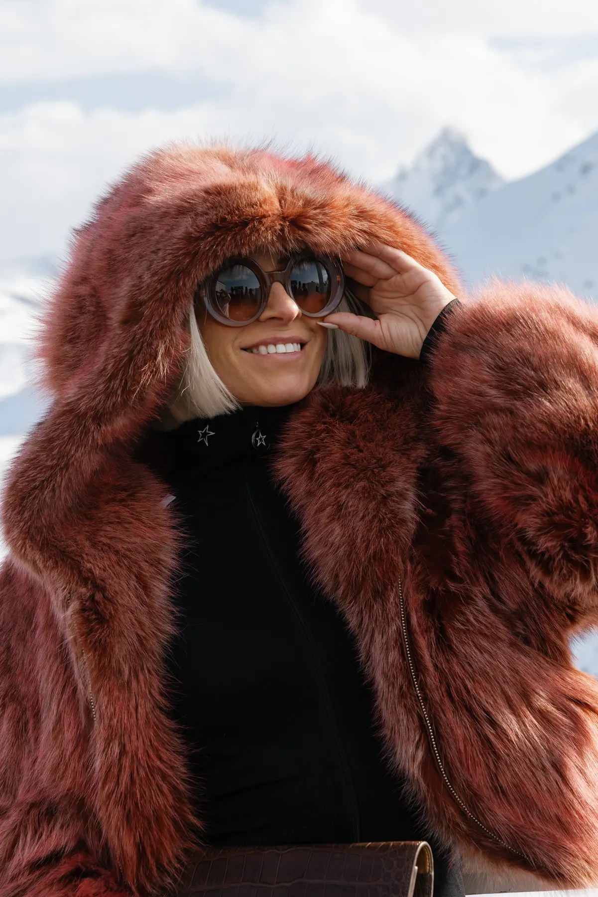 Woman wearing a fur jacket and sunglasses posing during a luxury ski holiday in Courchevel.