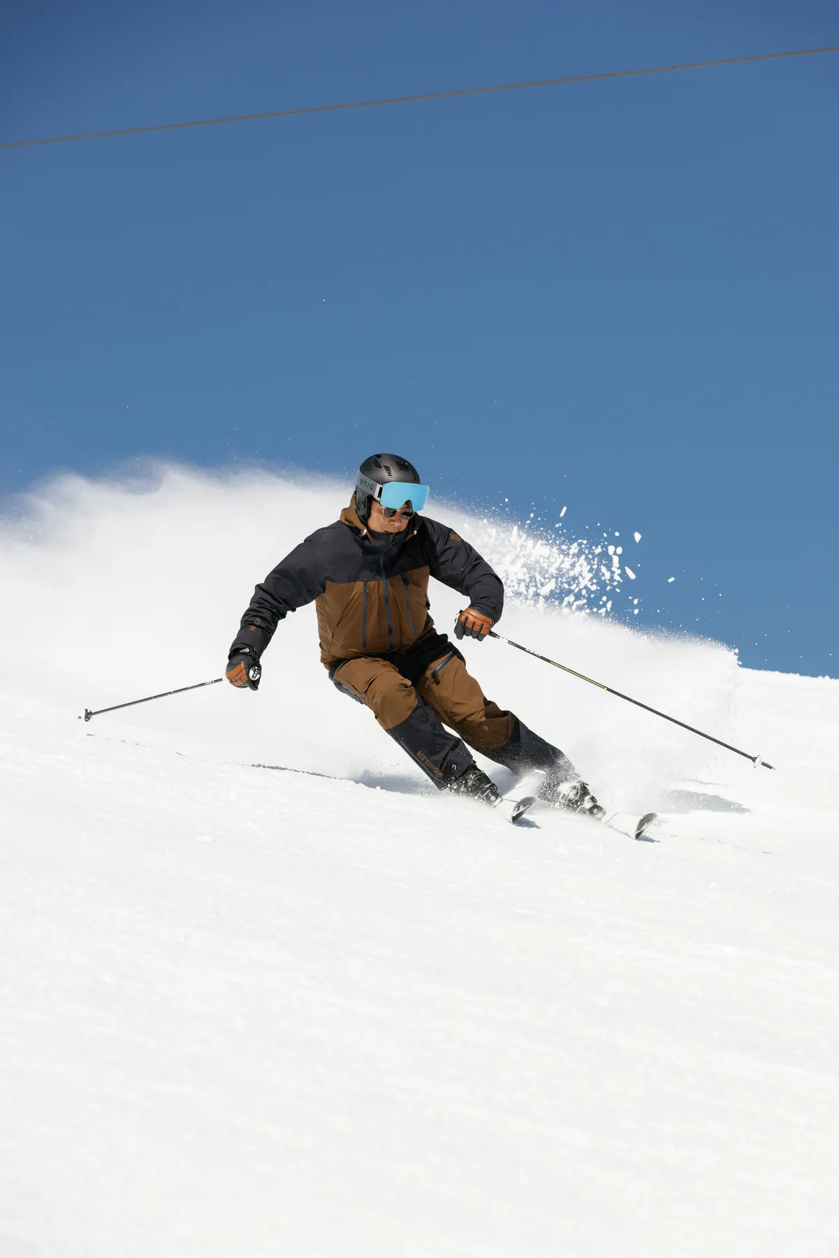 Skier wearing Moncler ski wear carving through fresh snow during a ski photography session in Courchevel.