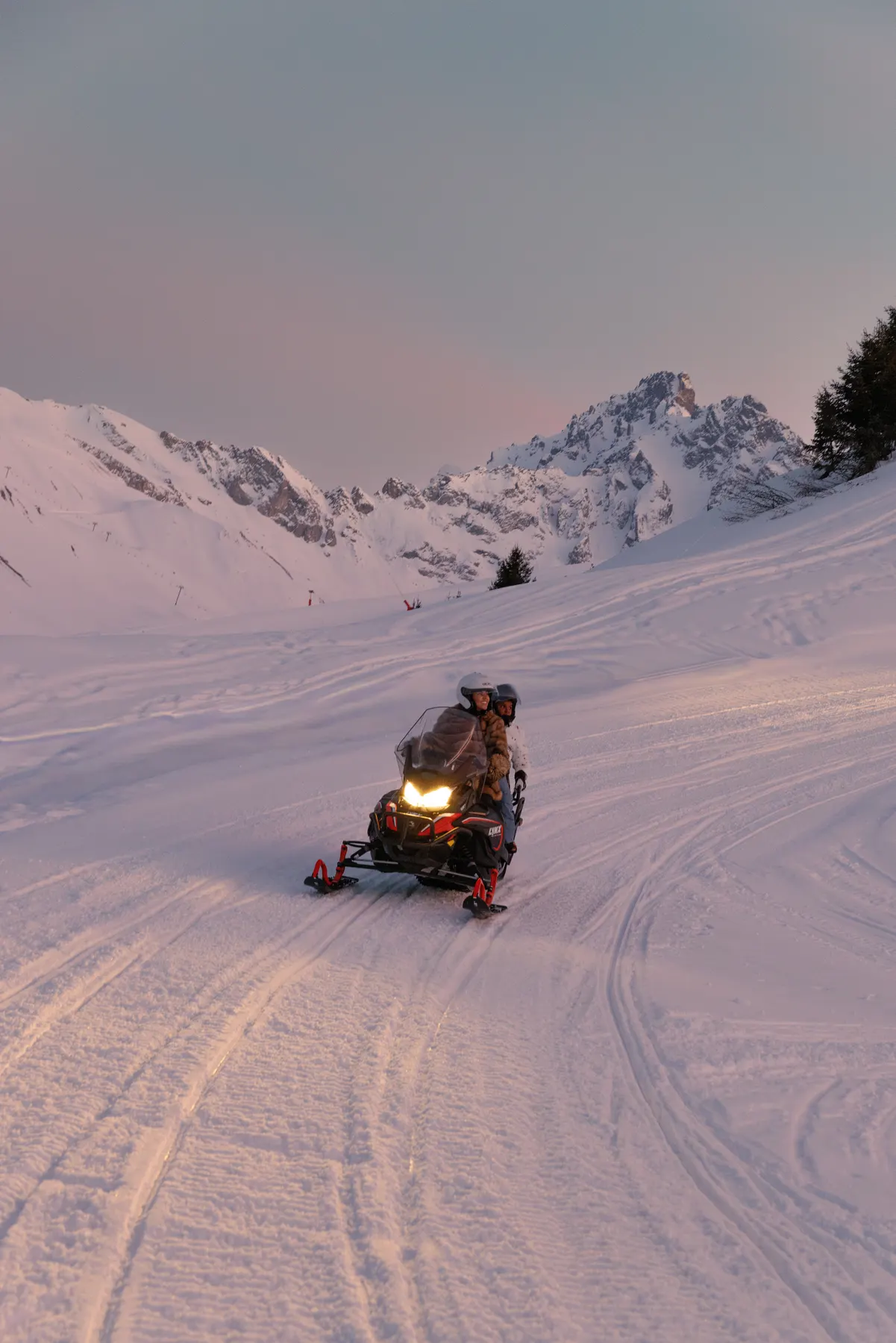 Snowmobile ride through the mountains at sunset during a winter holiday in Courchevel.