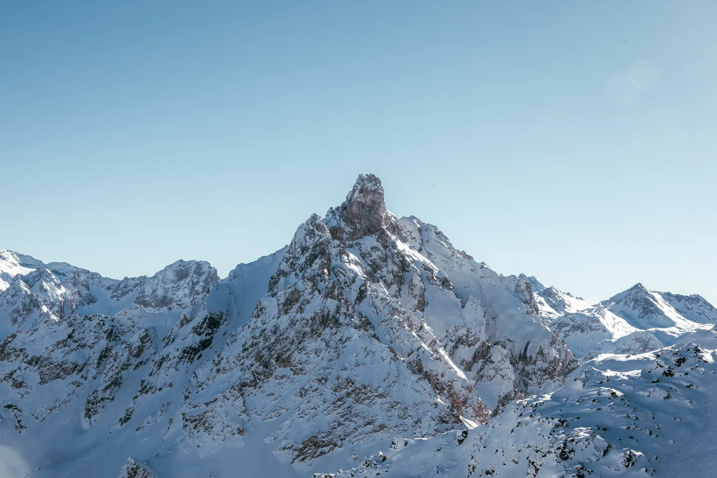 Snow-covered mountain peaks and alpine landscape in Courchevel under a clear blue sky.